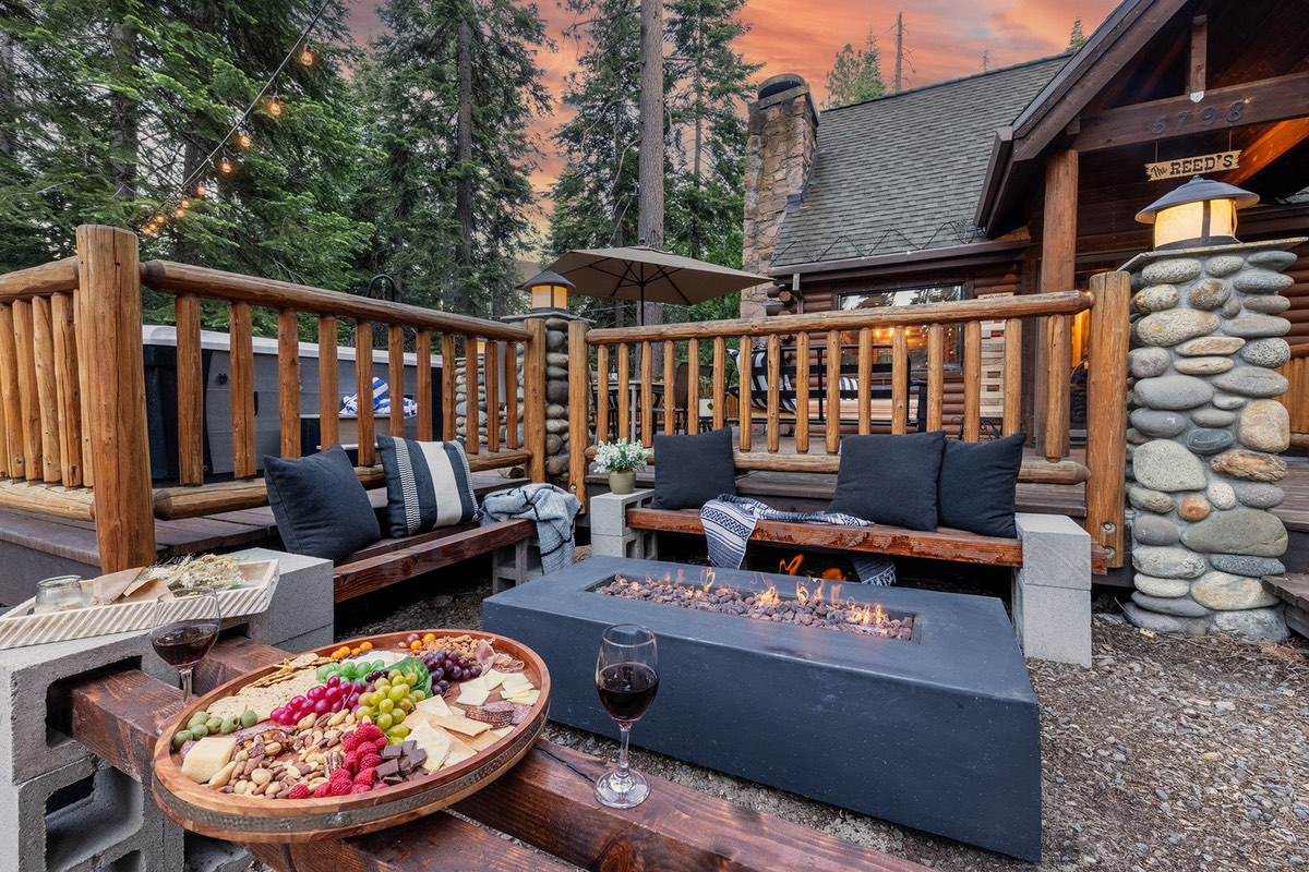 Gather the whole family around the fire pit as it catches — repurposed chairlift benches, a board of snacks, and the day winding down in gold.